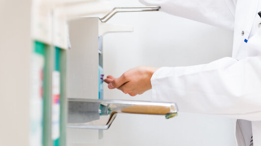 Klinikmitarbeitender desinfiziert Hände