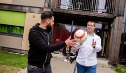 zwei Auszubildende mit Ball vor Gebäude