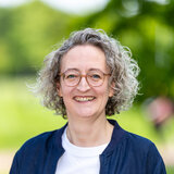 Portrait Anja Reuter vor Blaetterhintergrund