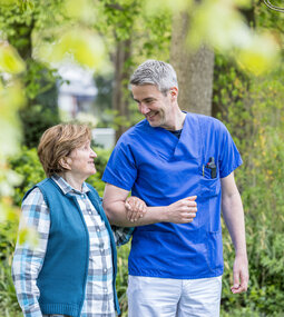 Ein Klinikmitarbeitender geht mit einer Patientin spazieren