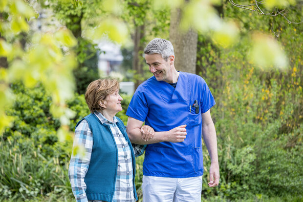 Ein Klinikmitarbeitender geht mit einer Patientin spazieren