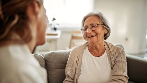 Klinikmitarbeiterin hält Hand von Patientin