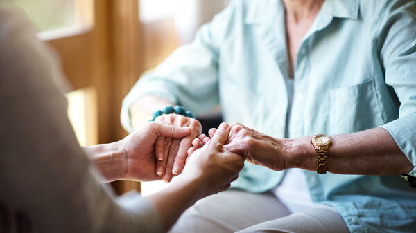 Angehörige hält Hände einer Patientin