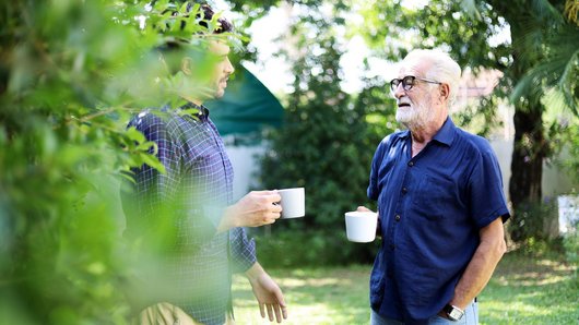 Zwei Männer trinken Kaffee im Garten
