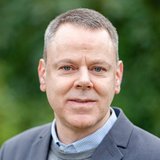 Kai Rettberg Portrait Kai Rettberg vor Blaetterhintergrund