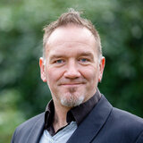 Portrait Dirk Tenfelde vor Blaetterhintergrund